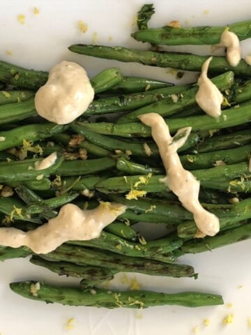green beans with a lemon tahini dressing on a white plate