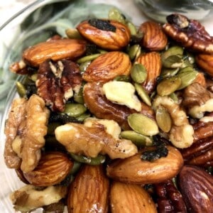 A bowl of roasted nuts with sage and rosemary.