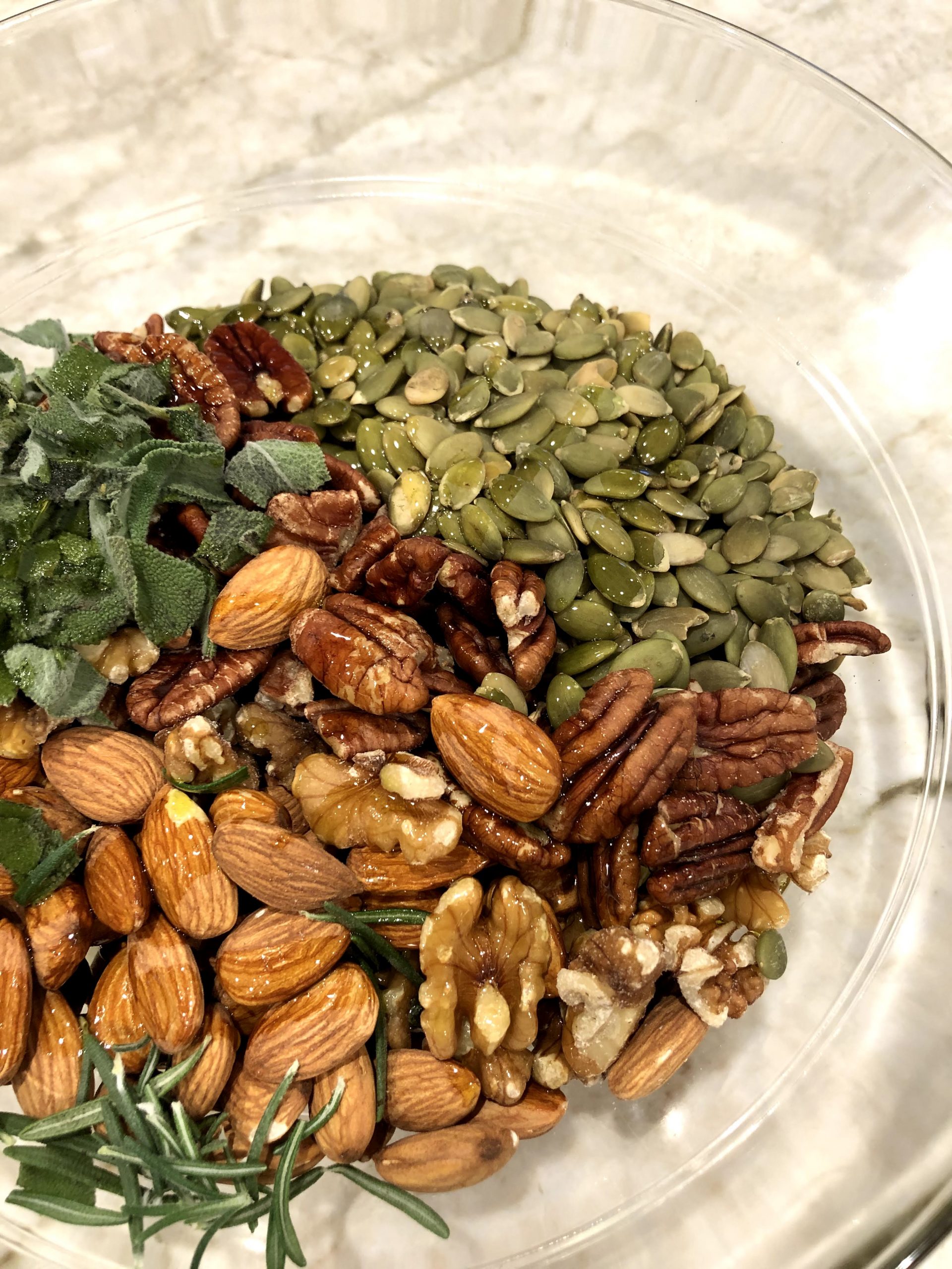 A bowl of nuts with sage and rosemary