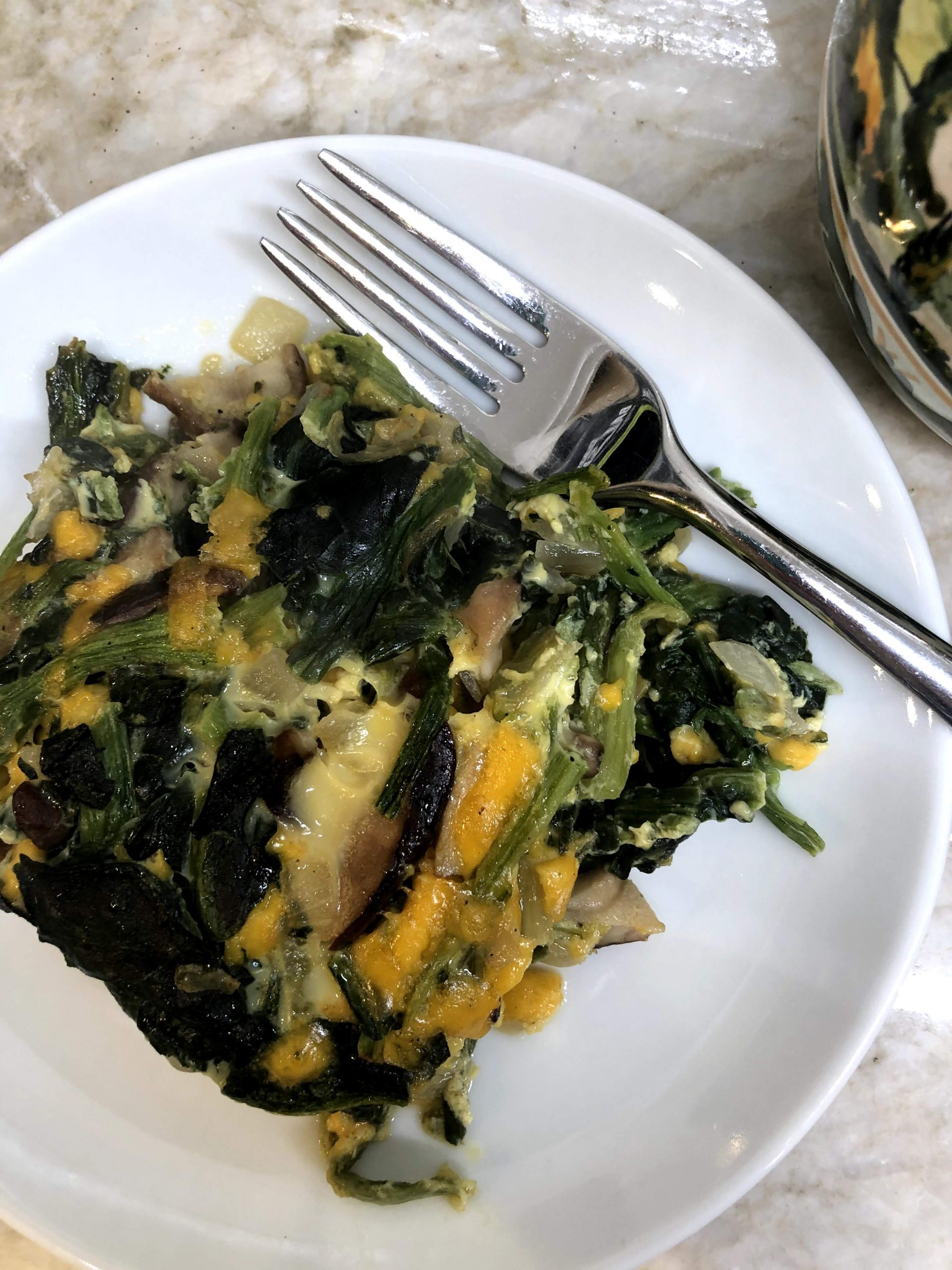 spinach casserole on a white plate with a fork