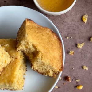 Cornbread stacked on a plate with honey in the background