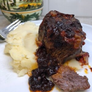 boneless beef short ribs with a barbecue sauce sitting on mashed potatoes