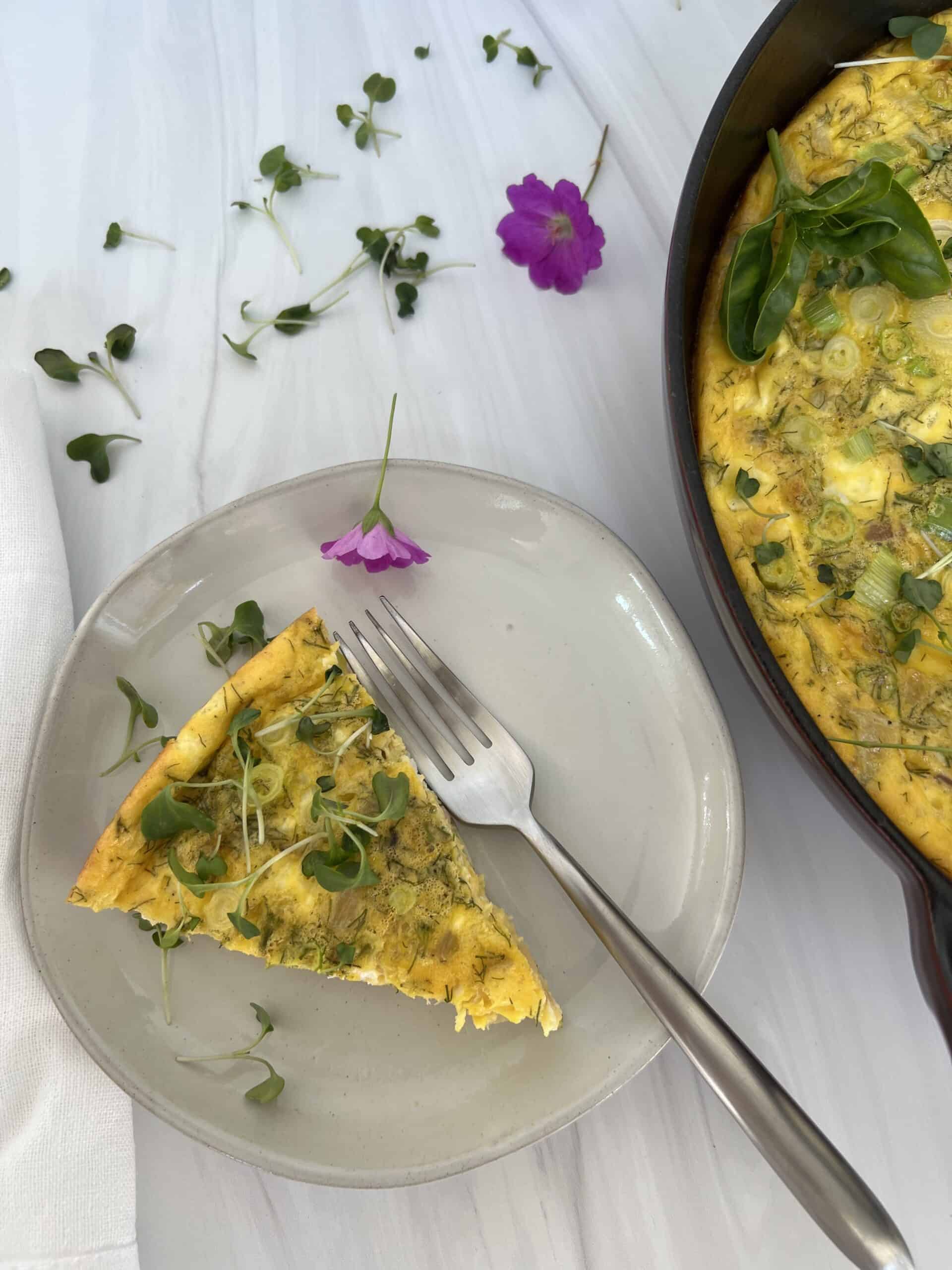 A slice of the frittata on a white plate with a fork. 