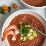 Bowl of The EASIEST Authentic Spanish Gazpacho Soup Recipe with shrimp and cucumber on top.