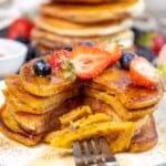 Easy Homemade Gluten-Free Pumpkin Pancakes on a white plate with strawberries.