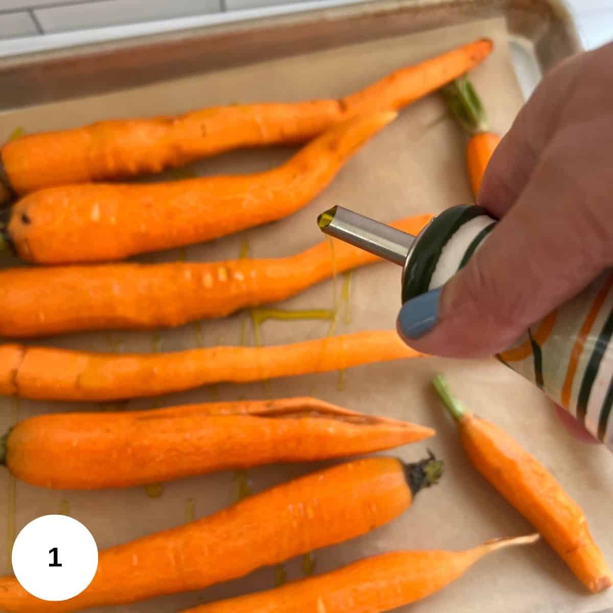 fresh carrots on a pan. drizzling olive oil on them for roasting.