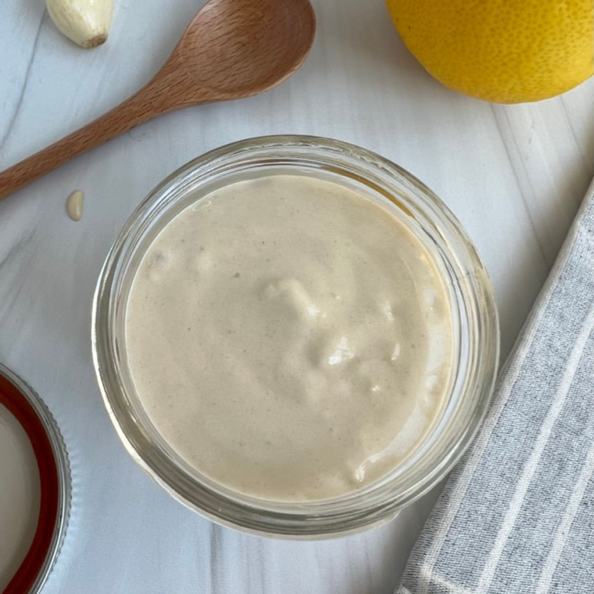 Best Healthy Lemon Garlic Tahini Sauce Recipe in a jar with a lemon and spoon