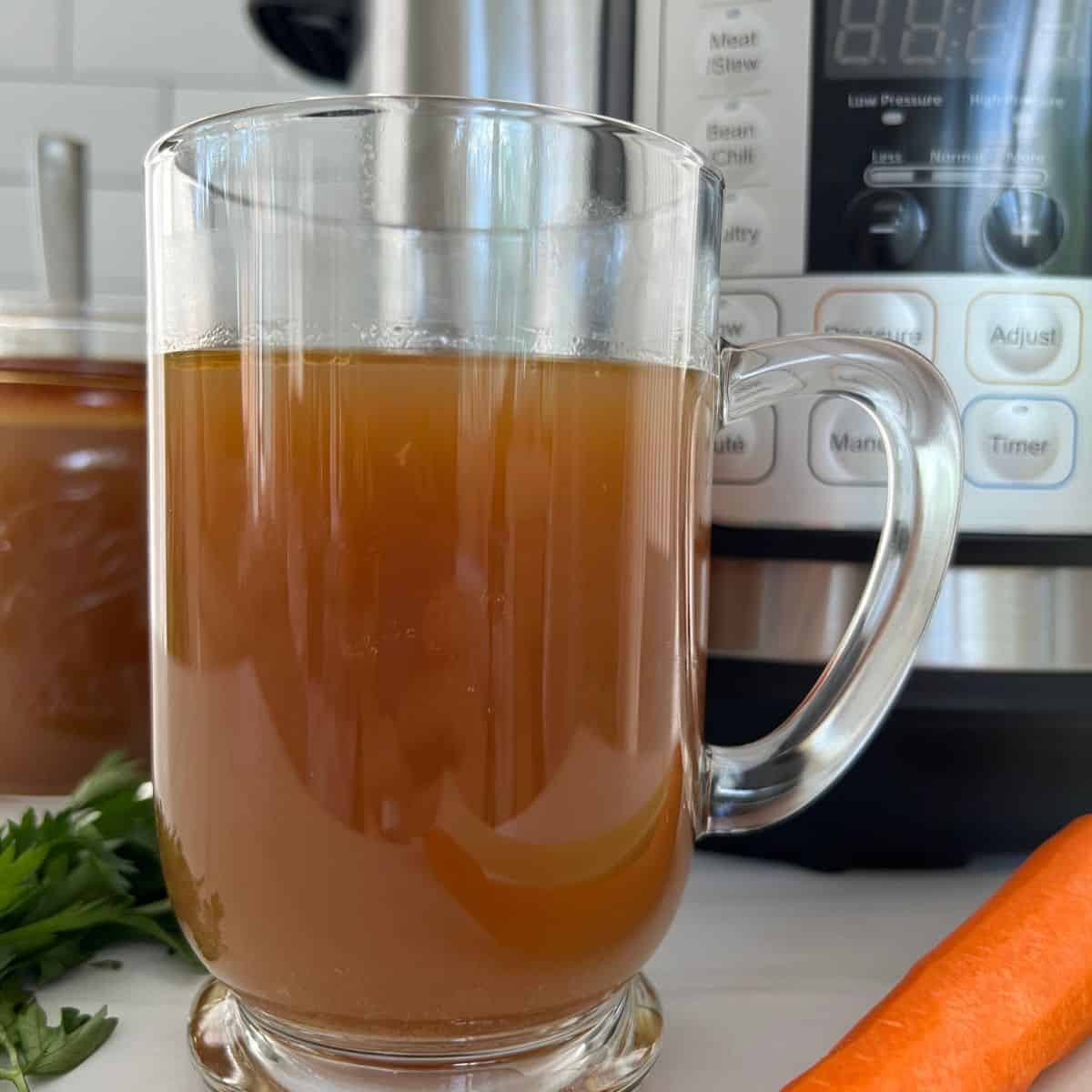 Bone broth in a glass mug with an instant pot in the background.