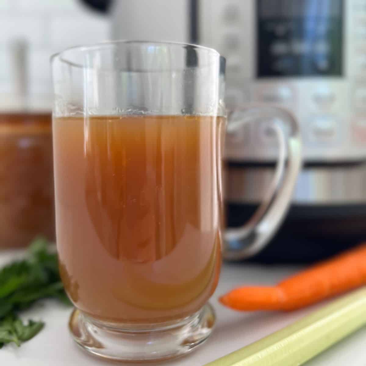 Bone broth in a clear mug with an instant pot in the background.