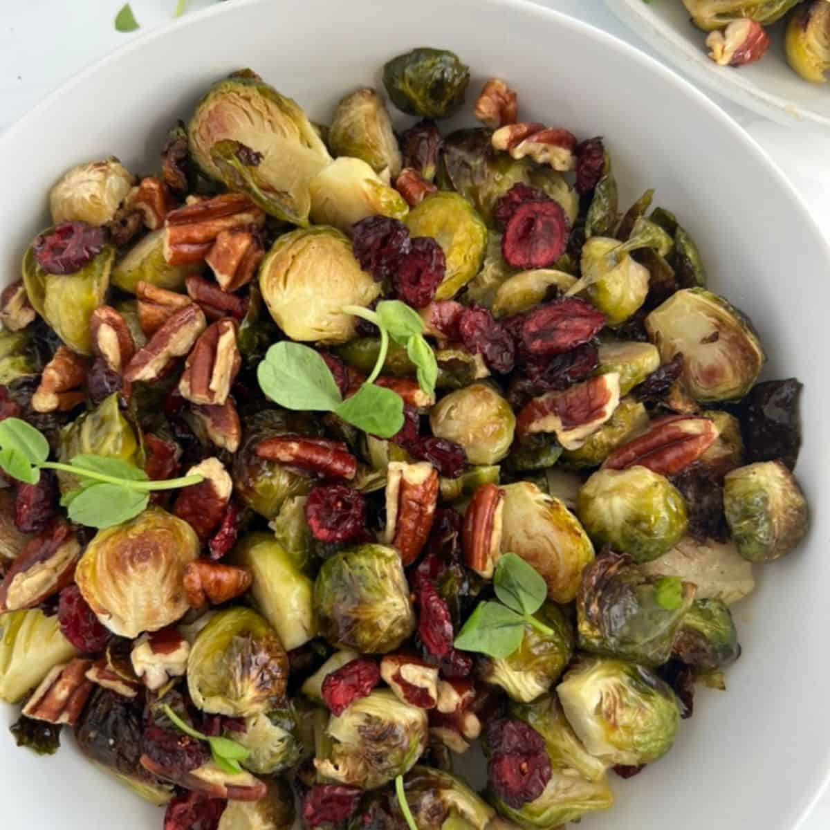 Roasted Brussels Sprouts With Pecans And Cranberries, With A Maple Dijon Vinaigrette with pea shoots for decoration