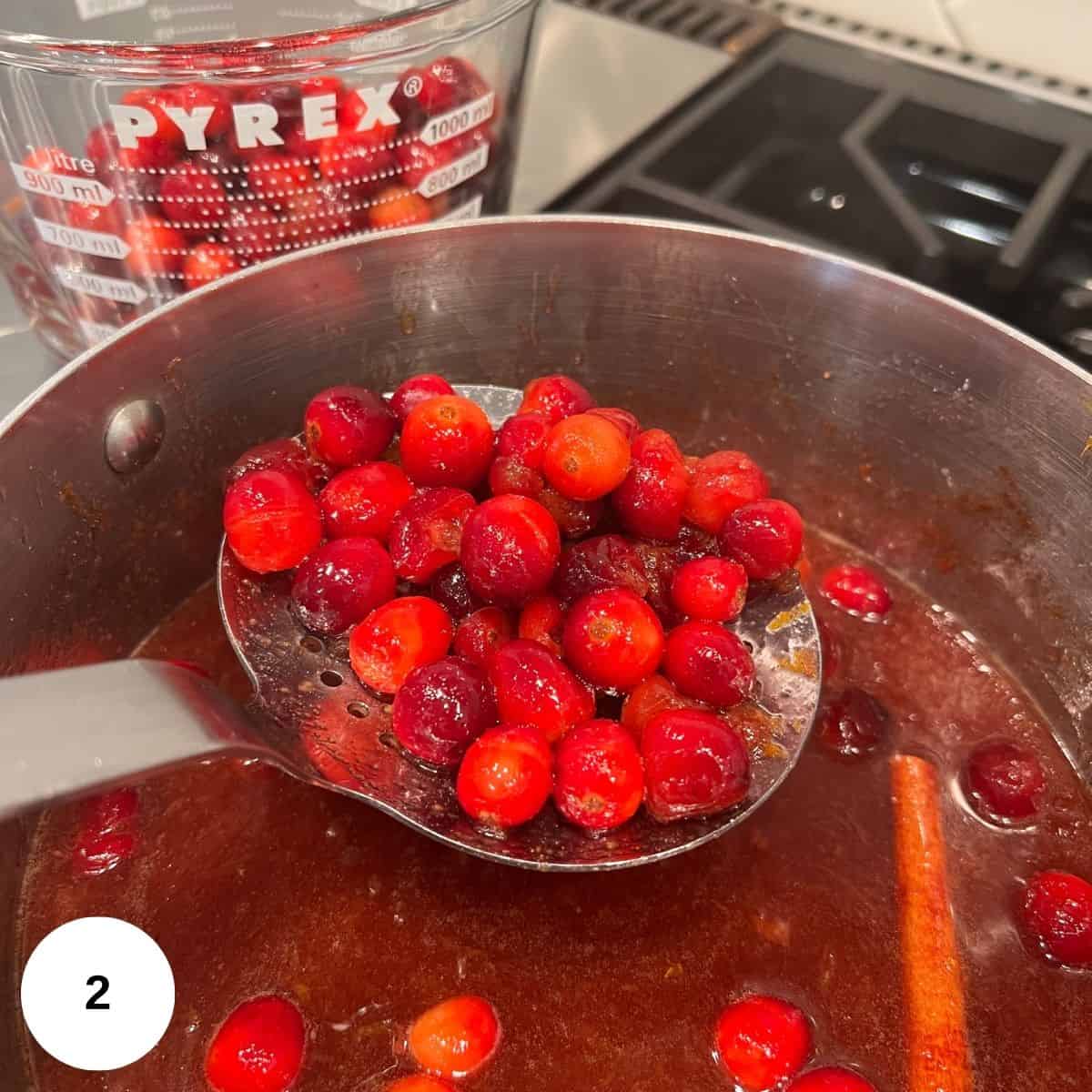 Sauce simmering on the stove and removing half of the cranberries to save. 