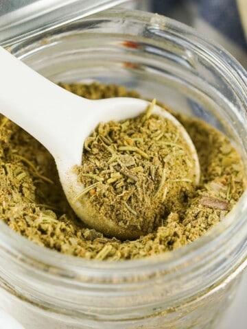Poultry seasoning spice blend in a jar with a white spoon.