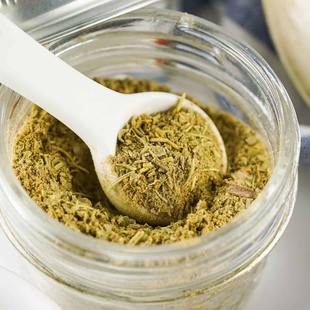 Poultry seasoning spice blend in a jar with a white spoon.