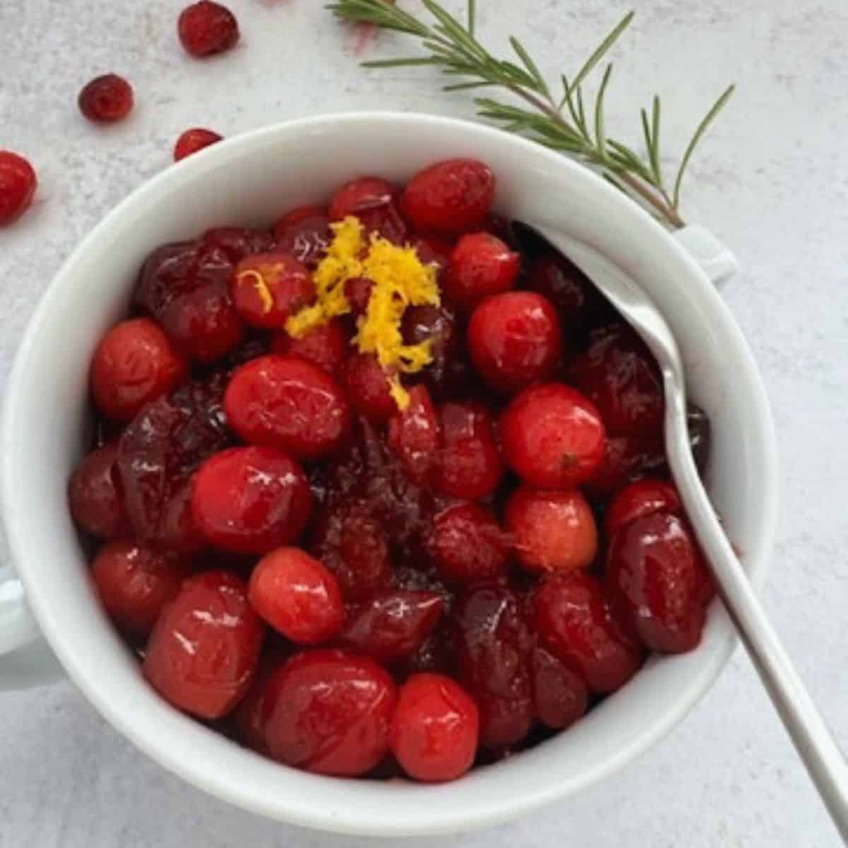 Homemade Organic Cranberry Sauce in a white bowl with a spoon. 