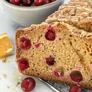 Orange Glazed Cranberry Bread with an orange and a bowl of cranberries