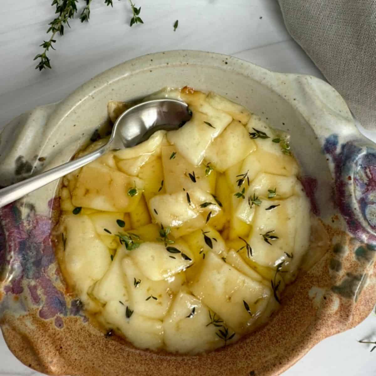 Portuguese Creamy Baked Cheese with Honey and Olive Oil with a spoon in a pan.