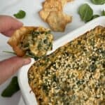Quick Spinach And Crab Dip Featured Image. Holding a cracker with some dip on it.