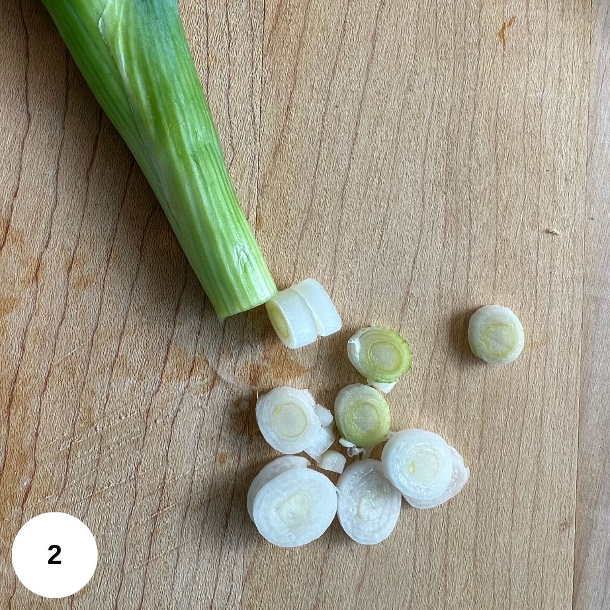 A cut up leek on a wooden cutting board. 