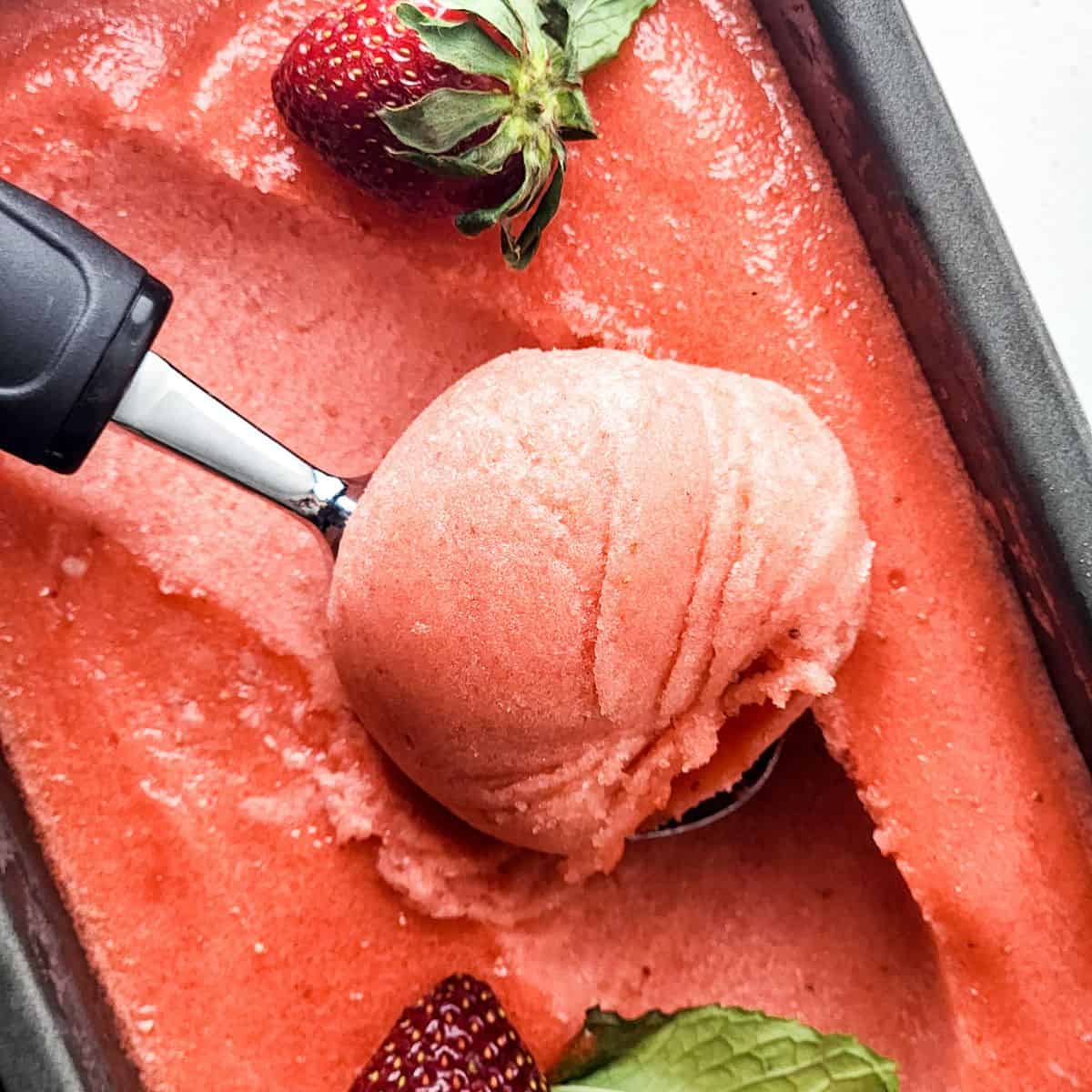 Strawberry lemonade sorbet being scooped out of the pan.