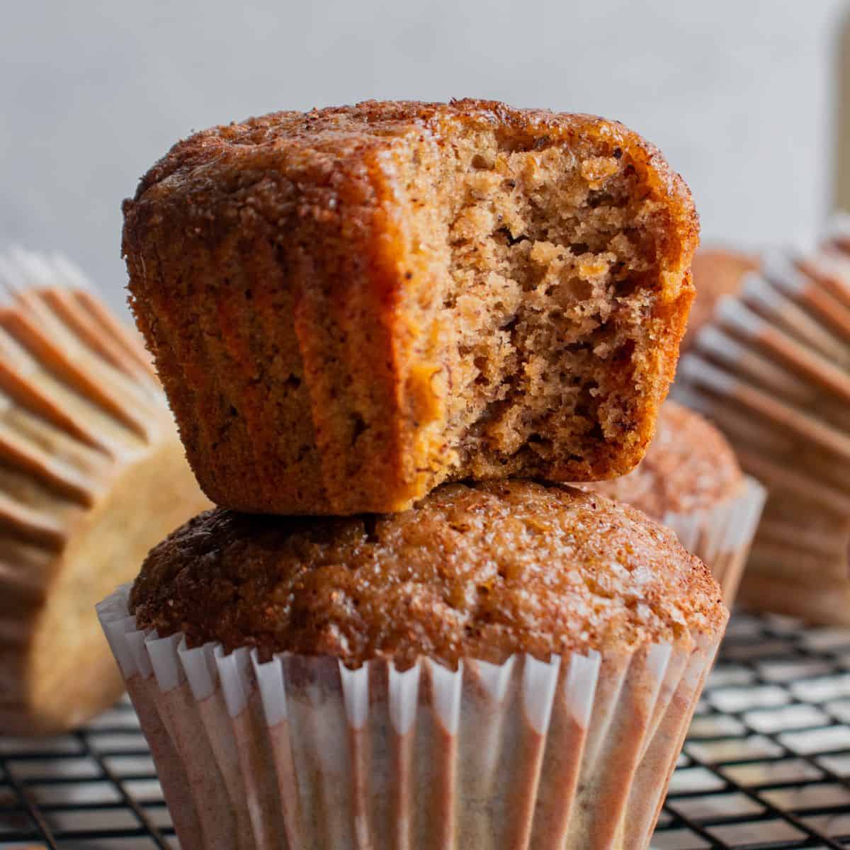 banana pumpkin muffins stacked on top of each other with the top one half eaten. 