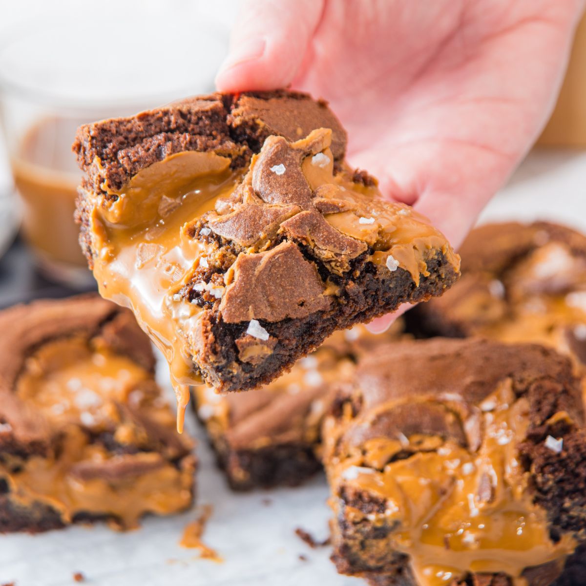 Holding a biscoff brownie and showing other brownies on parchment paper. 