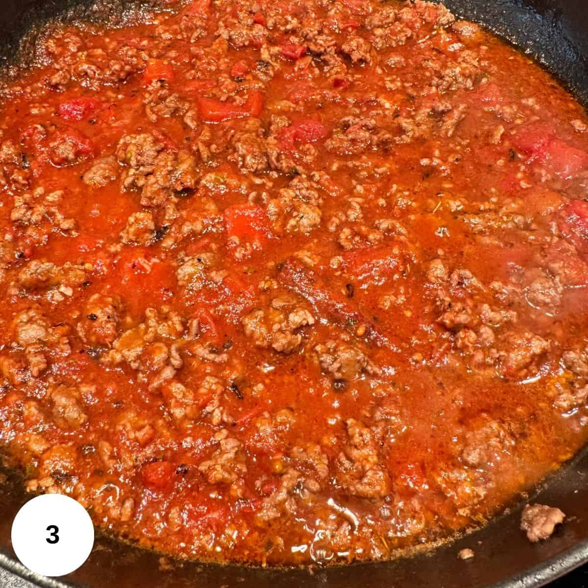 Adding wine and tomatoes to the lamb and then reducing the sauce on the stove. 