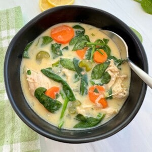 Greek Chicken Soup in a black bowl with a spoon.