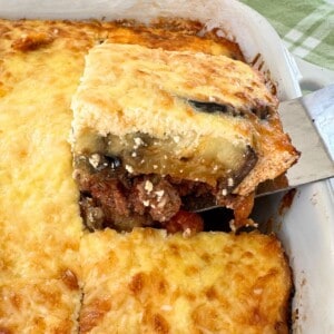 Lamb moussaka being lifted with a spatula out of the casserole to show the layers.