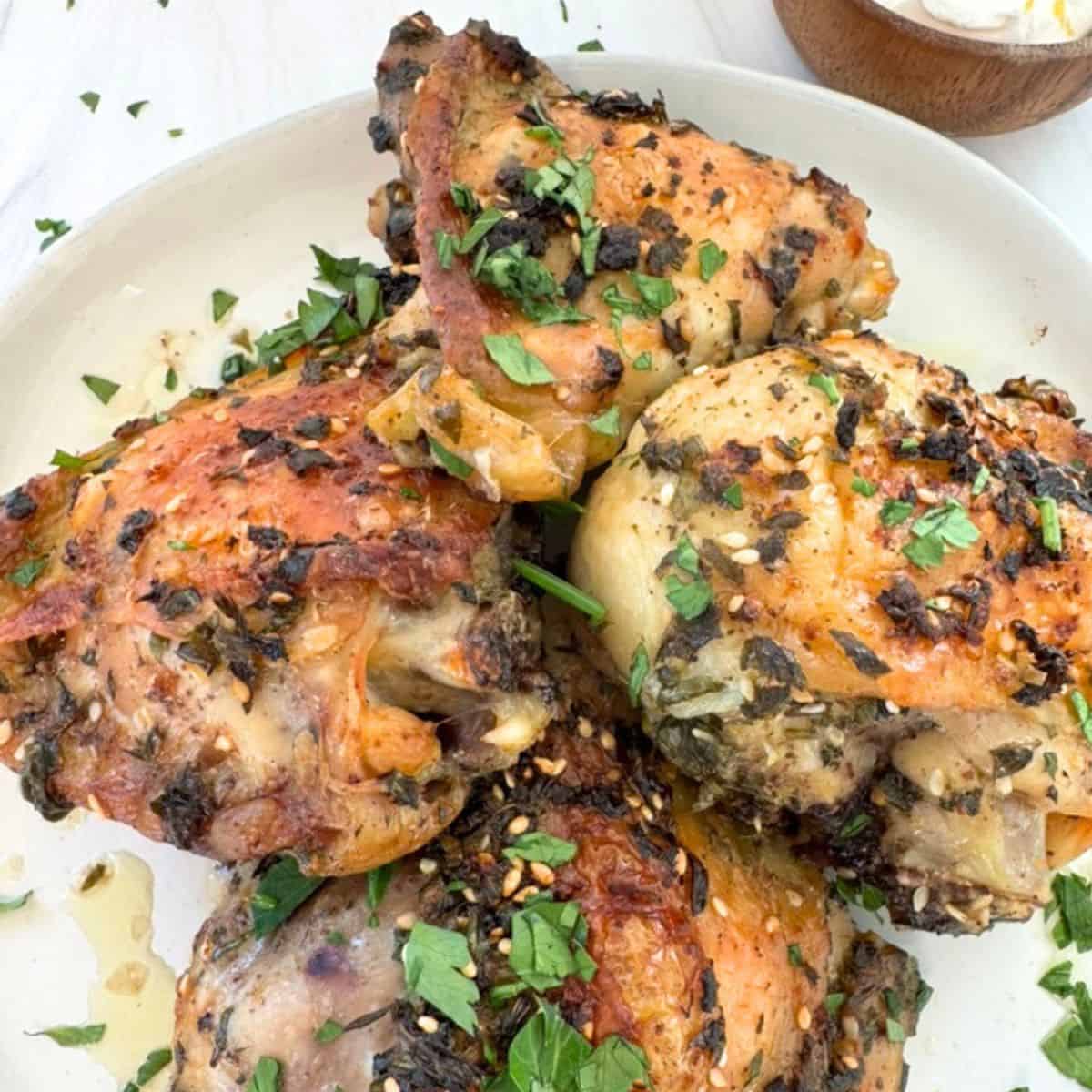 Marinated Middle Eastern chicken thighs baked and placed on a white plate. 