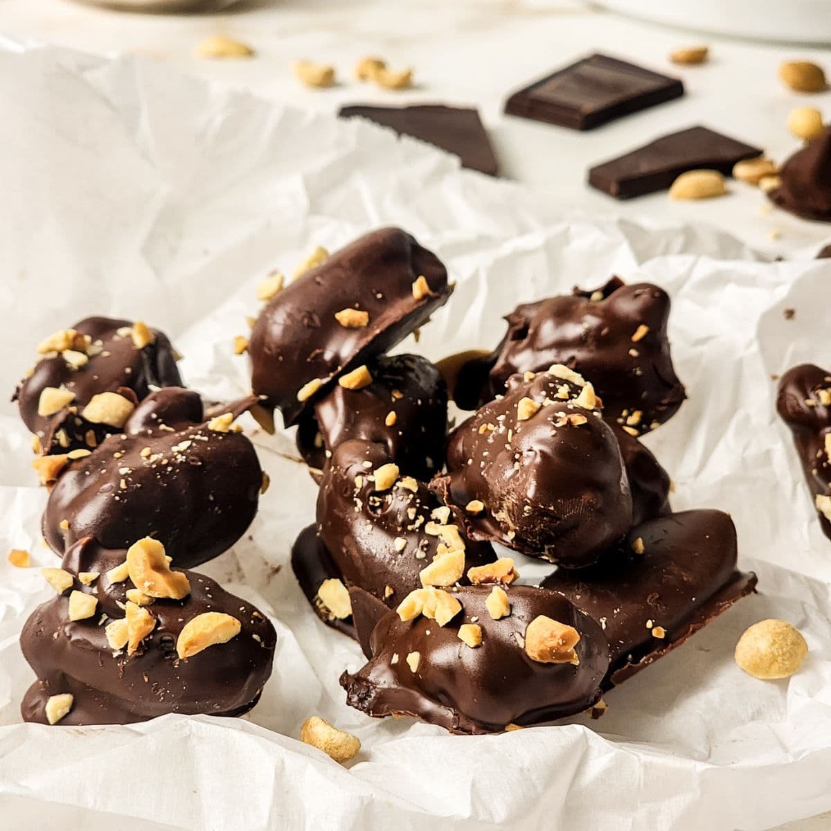 Chocolate covered stuffed dates on parchment paper and stacked on top of each other. 
