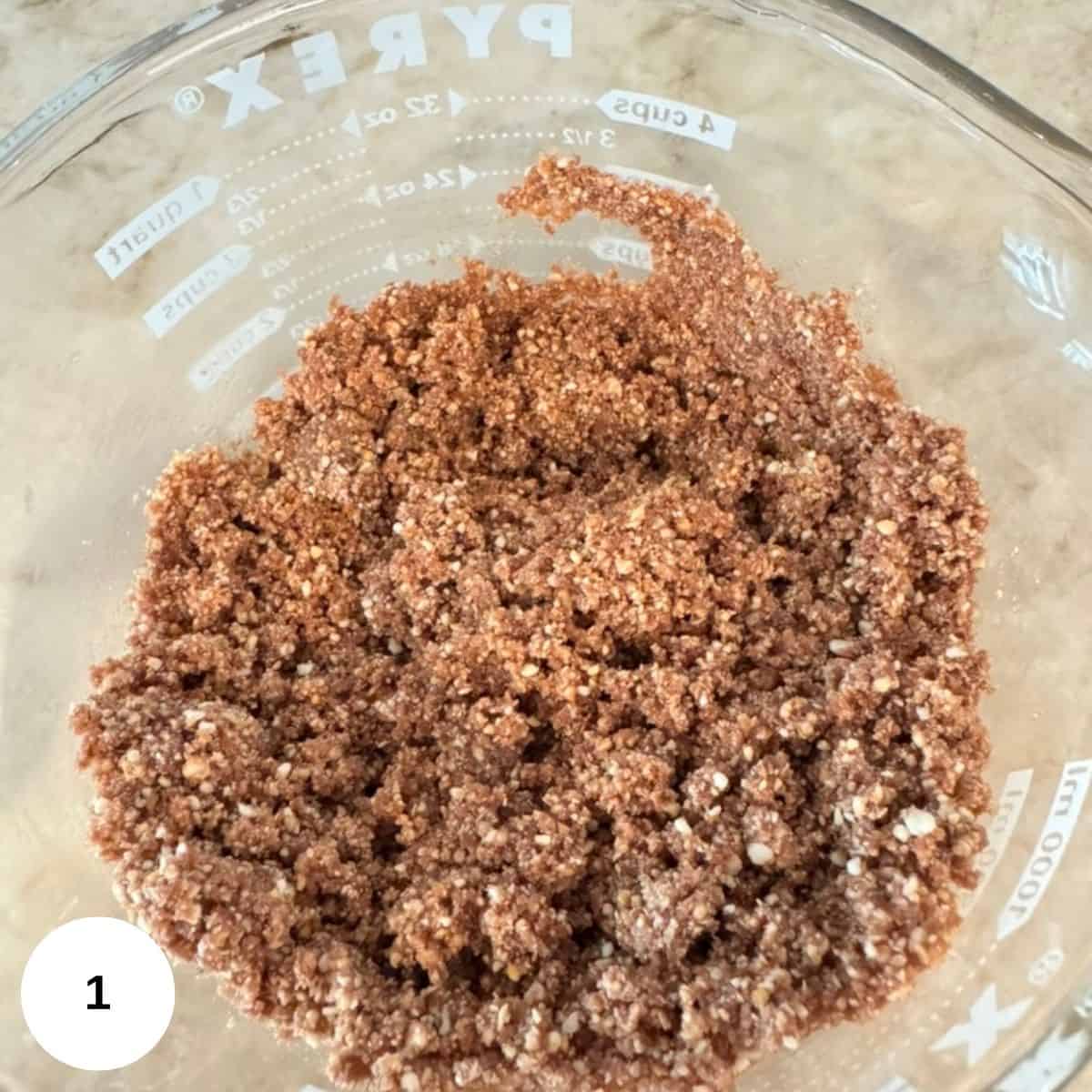 A glass Pyrex bowl contains a mixture of crust mix, placed on a light-colored countertop.