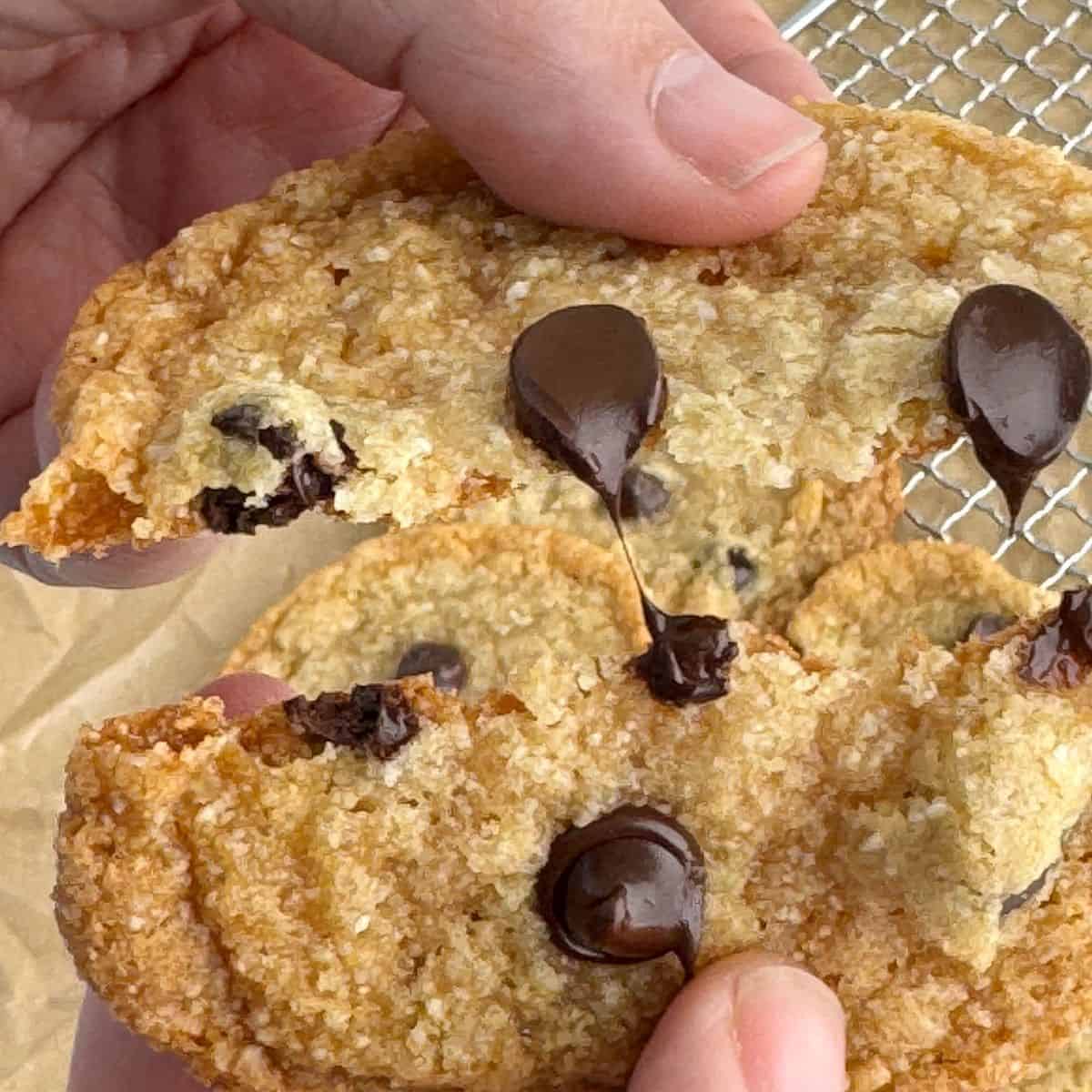 Showing how gooey the chocolate is by pulling the cookie apart. 