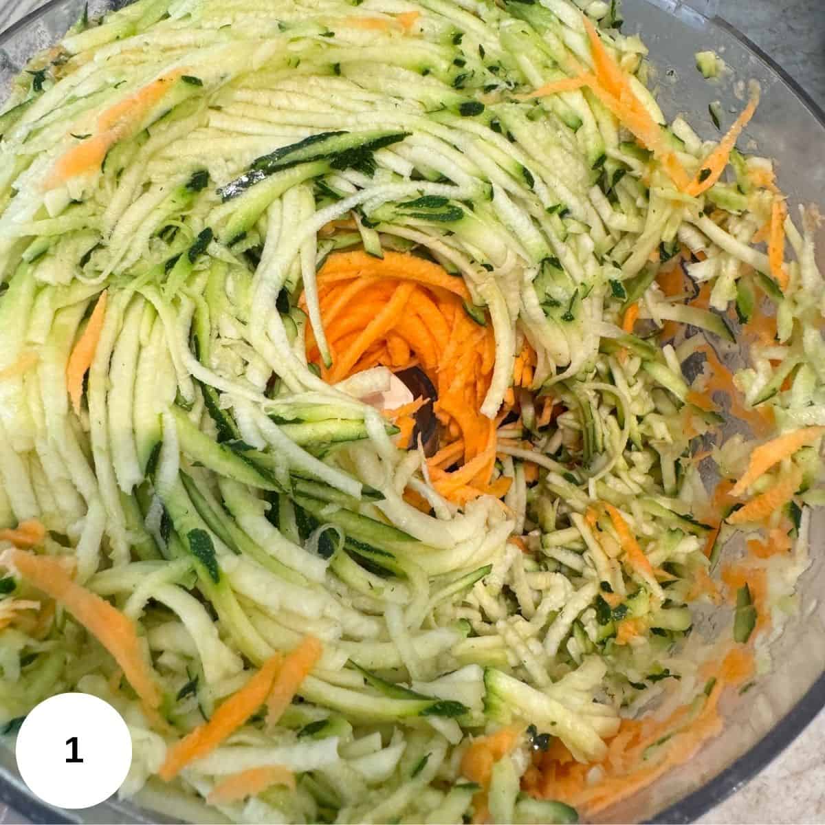 Shredding the potatoes, sweet potatoes, and the zucchini in a food processor. 
