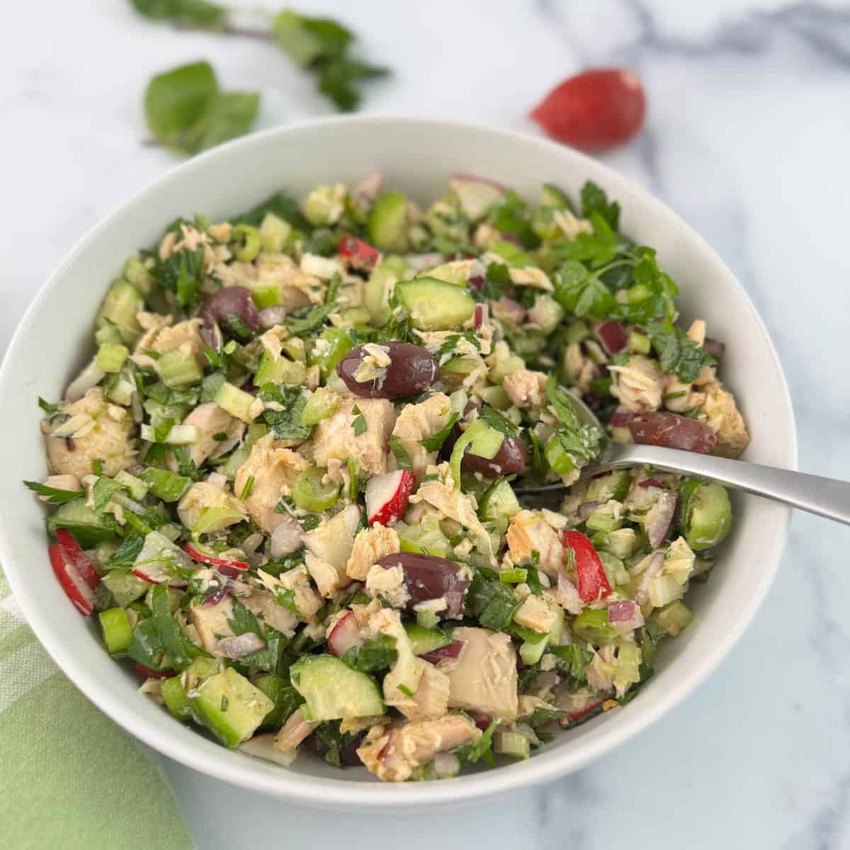 Mediterranean tuna salad with a spoon in the bowl. 