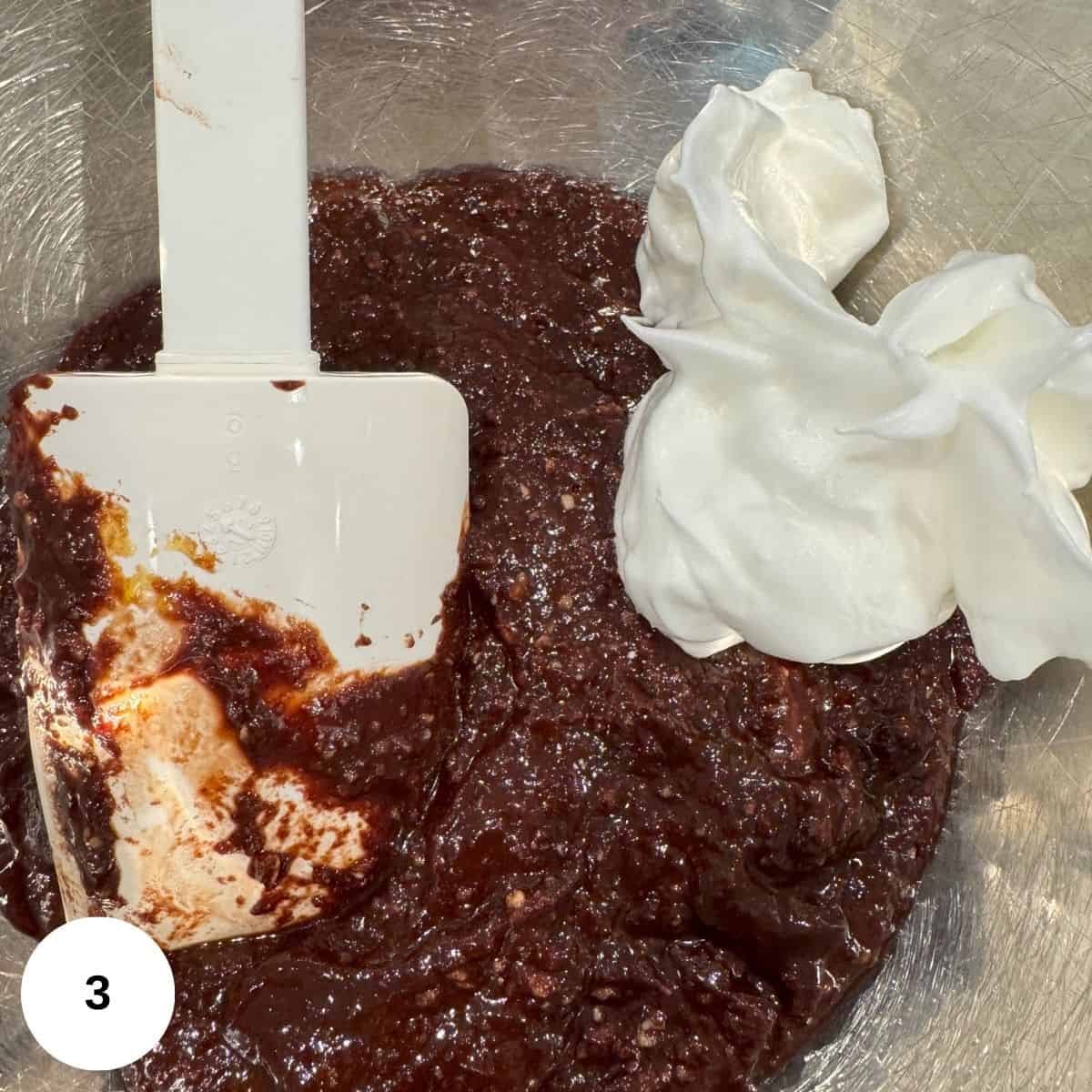 Adding whipped egg whites to the chocolate to create the cake. 