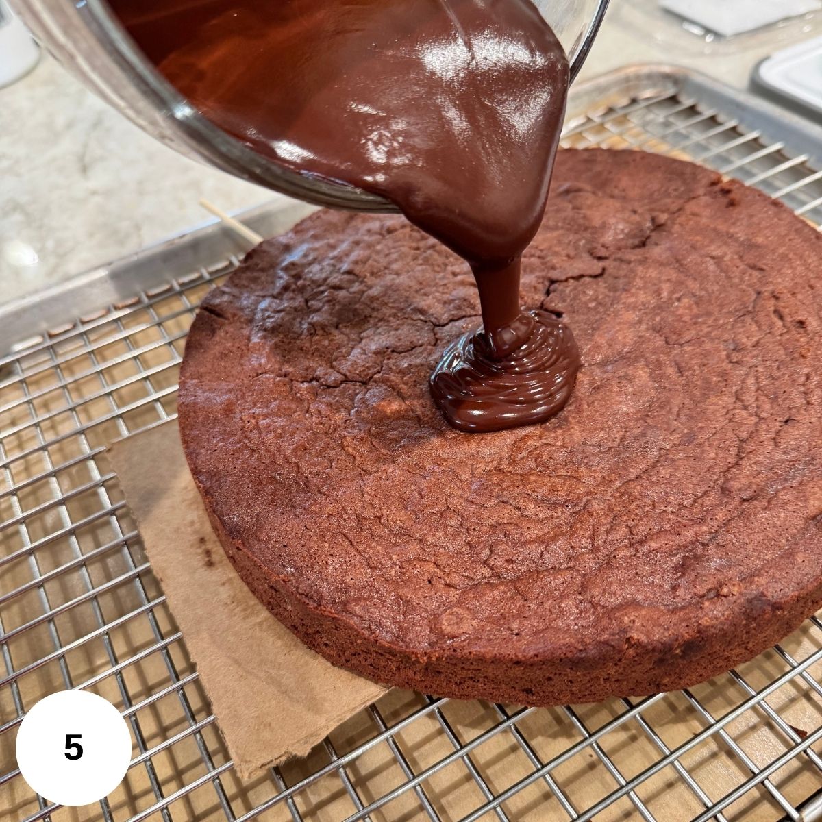 Pouring the ganache over the baked cake that is sitting on a wire rack. 