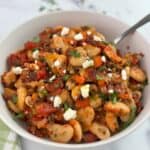 Greek baked beans, gigante plaki, in a white bowl with a spoon.