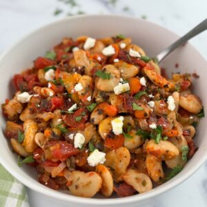 Greek baked beans, gigante plaki, in a white bowl with a spoon.