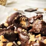 Chocolate covered stuffed dates stacked on top of each other and one is half eaten.