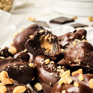 Chocolate covered stuffed dates stacked on top of each other and one is half eaten.