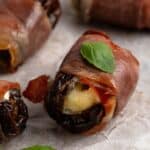 Proscuitto wrapped date sitting on parchment paper.