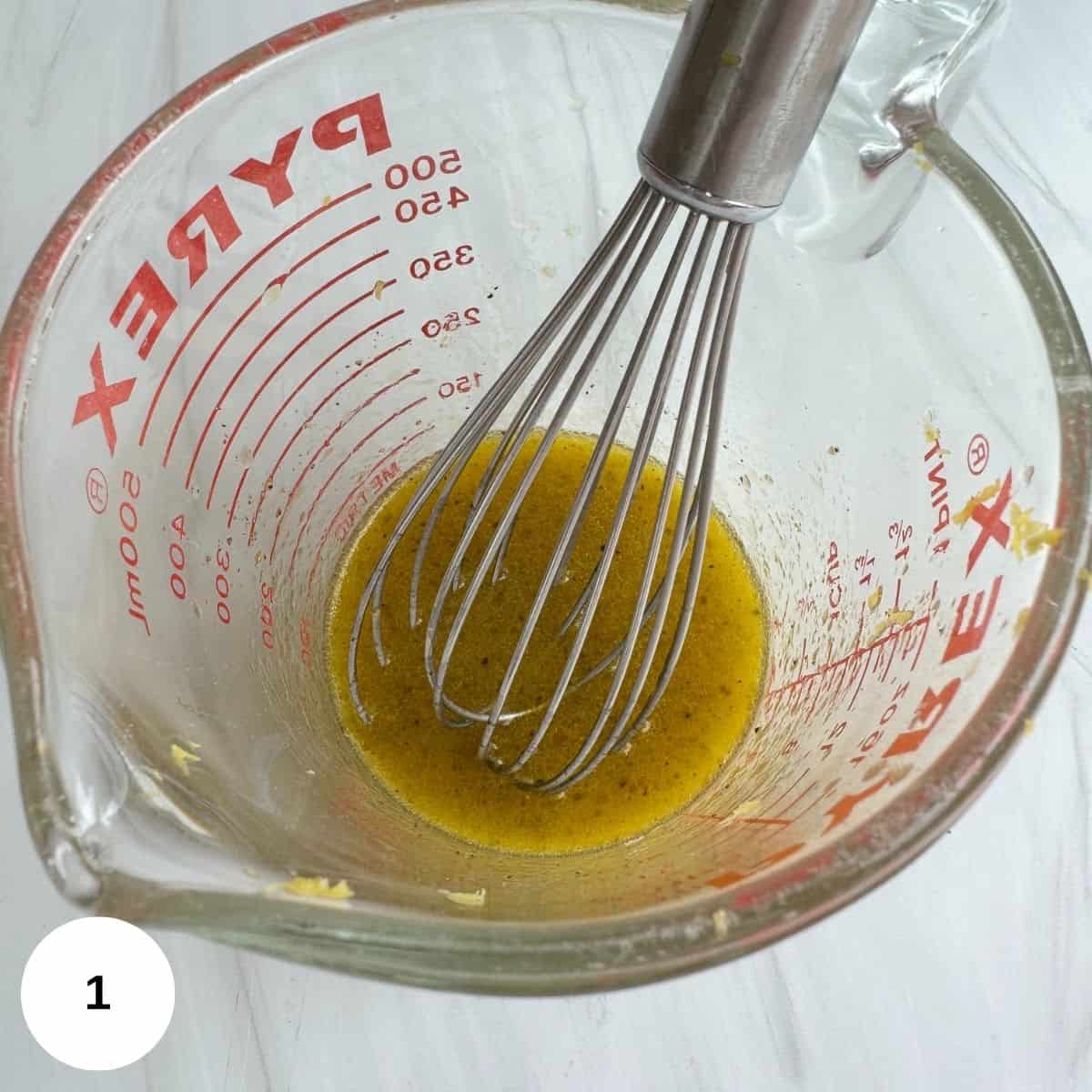 Whisking the dressing ingredients in a measuring bowl.