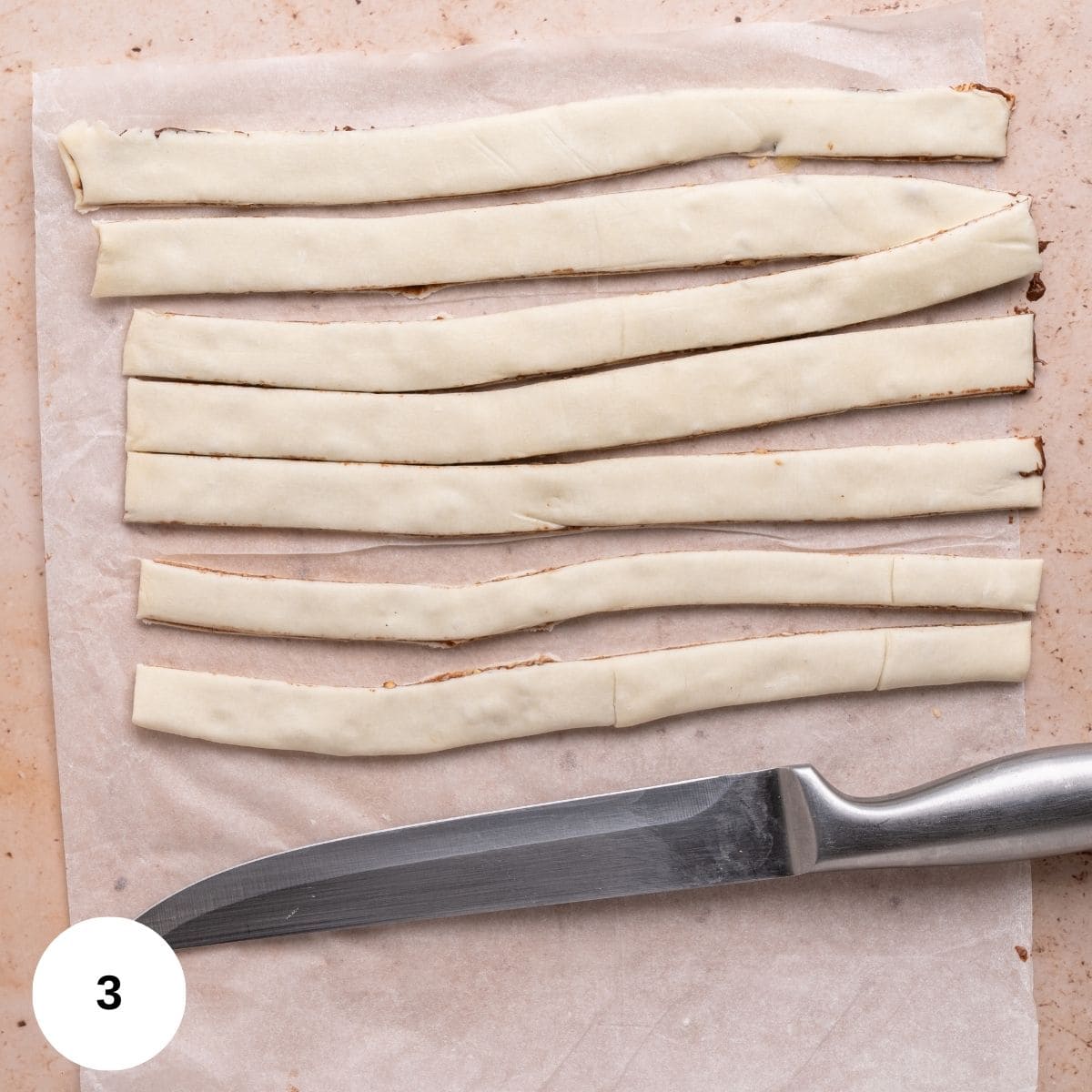 Cutting the puff pastry with a knife to create strips.