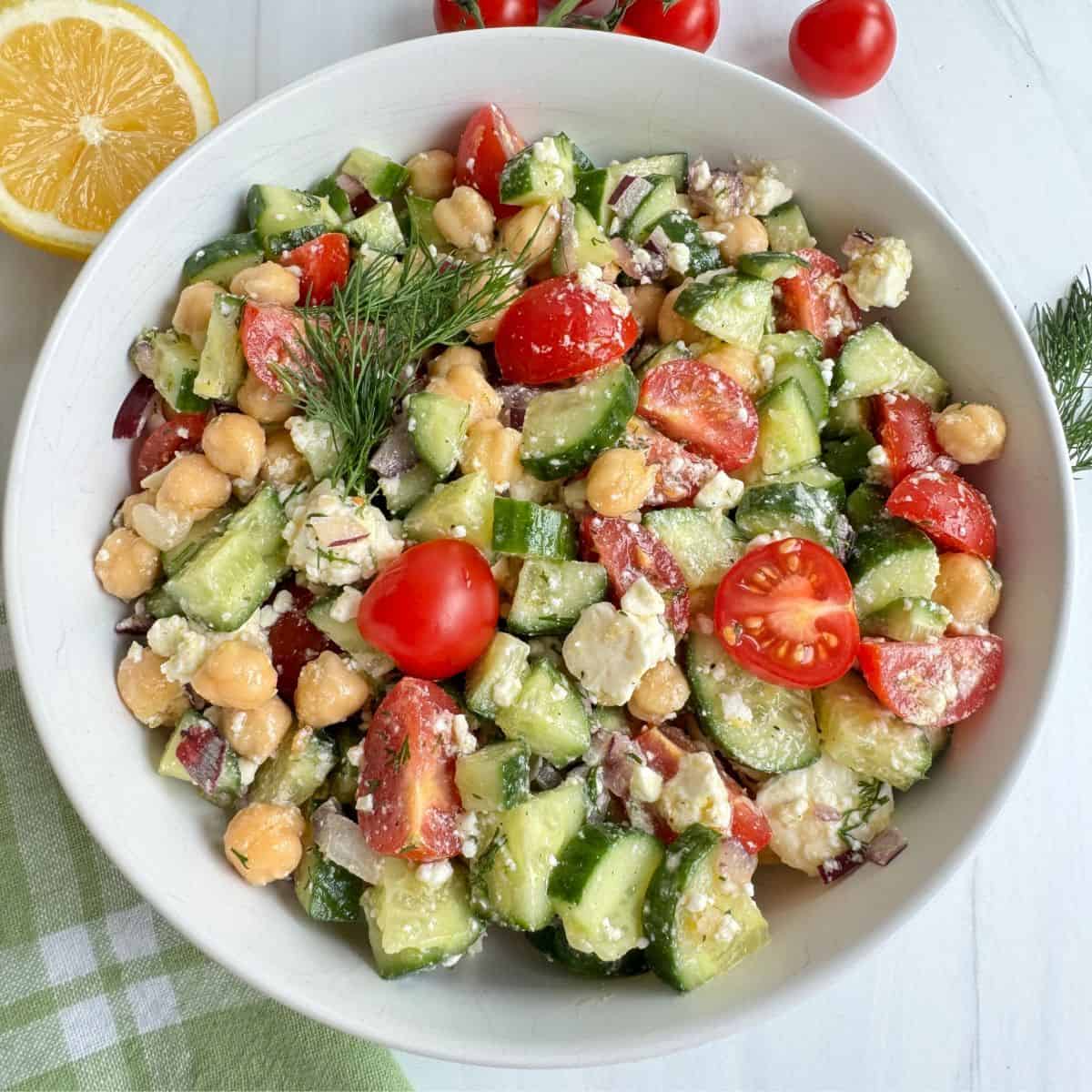 Chickpea Cucumber Feta Salad in a white bowl with a sprig of dill on top.