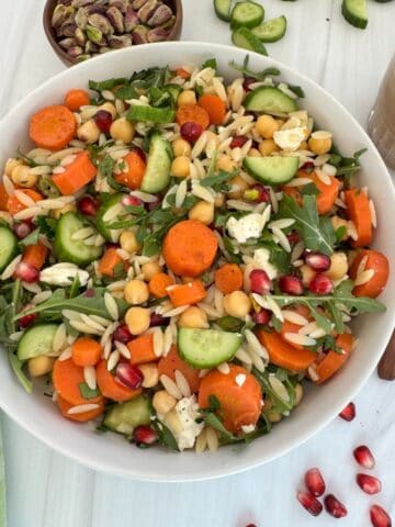 Chickpea Orzo Salad in a white bowl with the dressing on the side.