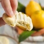 Someone holding a lemon poppy seed cookie after having taken a bite out of it.