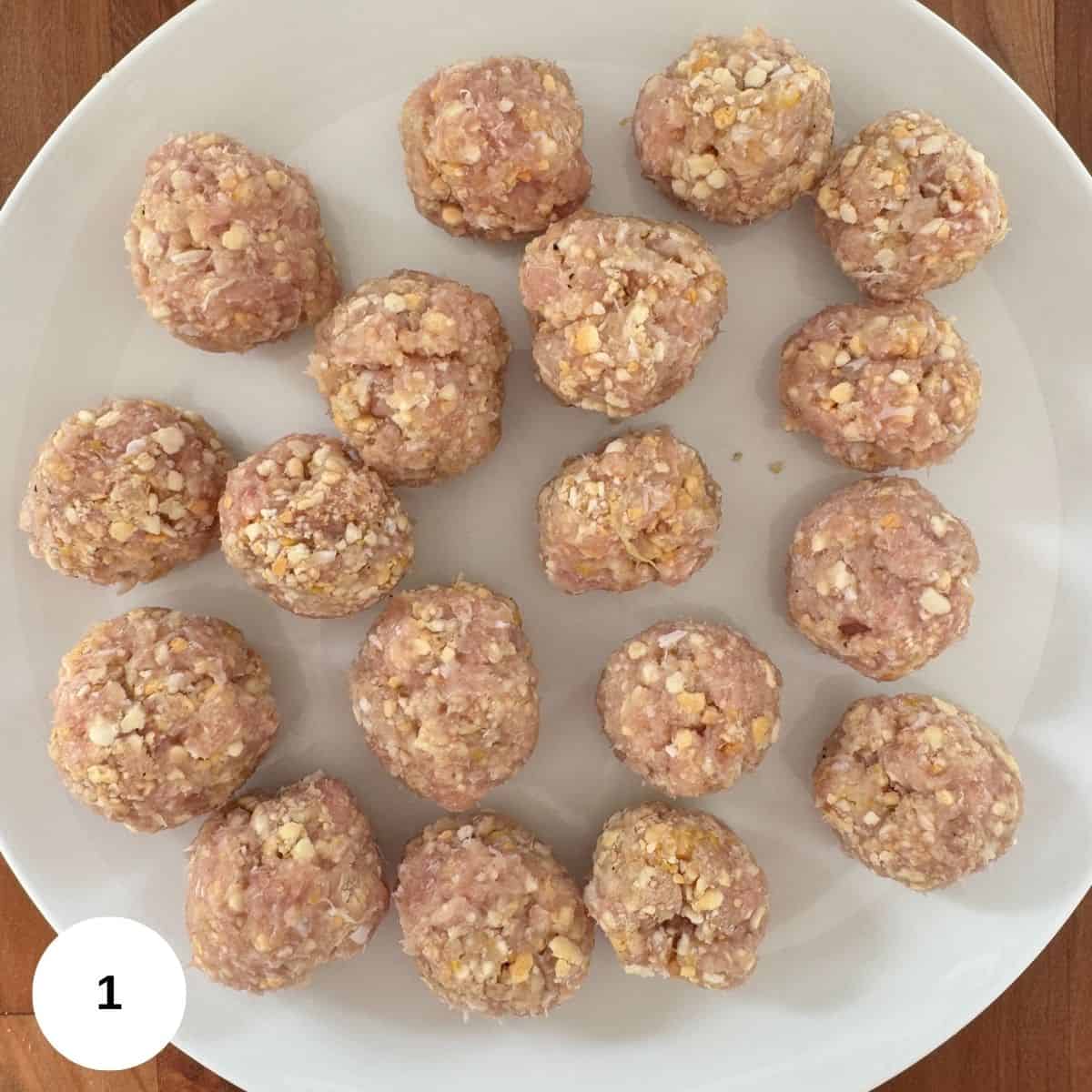 Meatballs sitting on a plate waiting to be cooked.