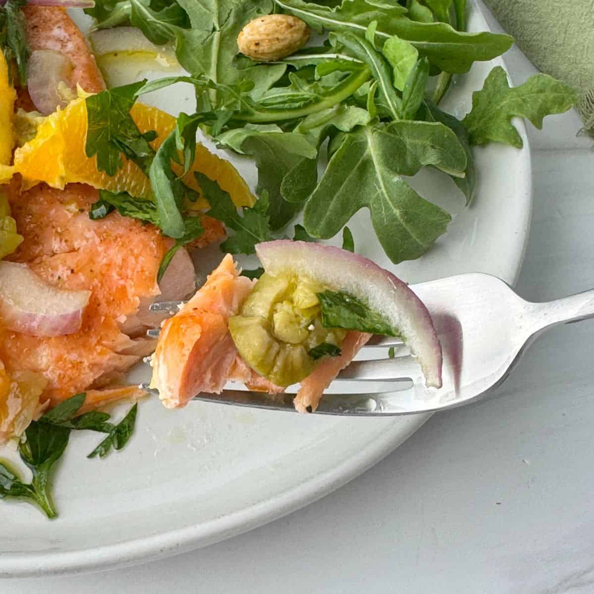 Holding a fork of salmon and relish.