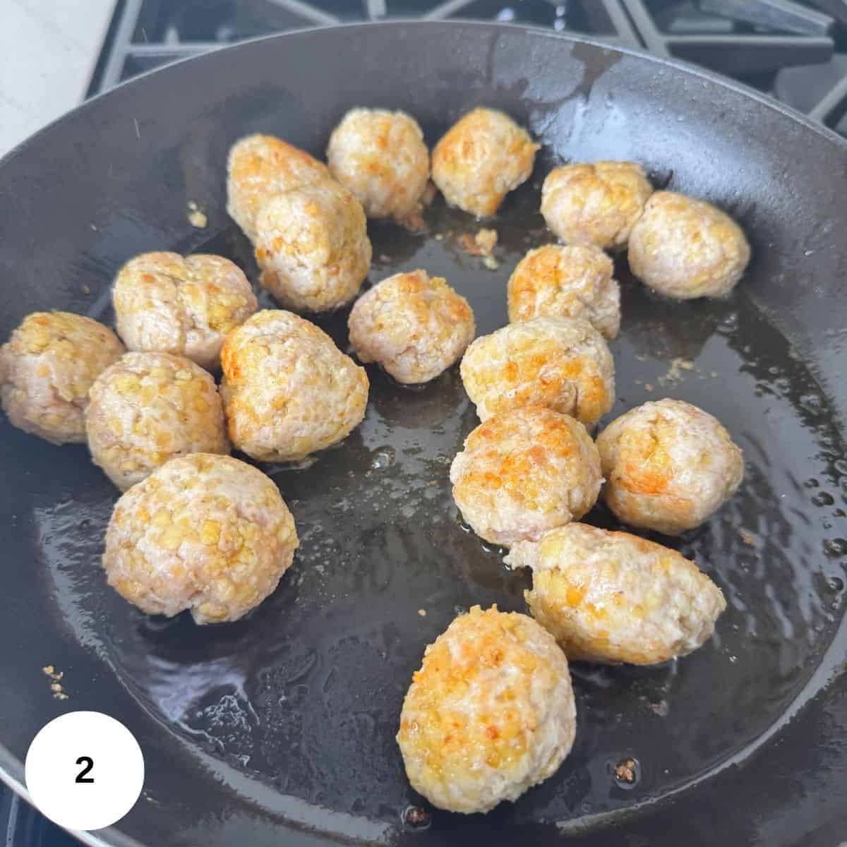 Cooking the meatballs in a pan on the stove.