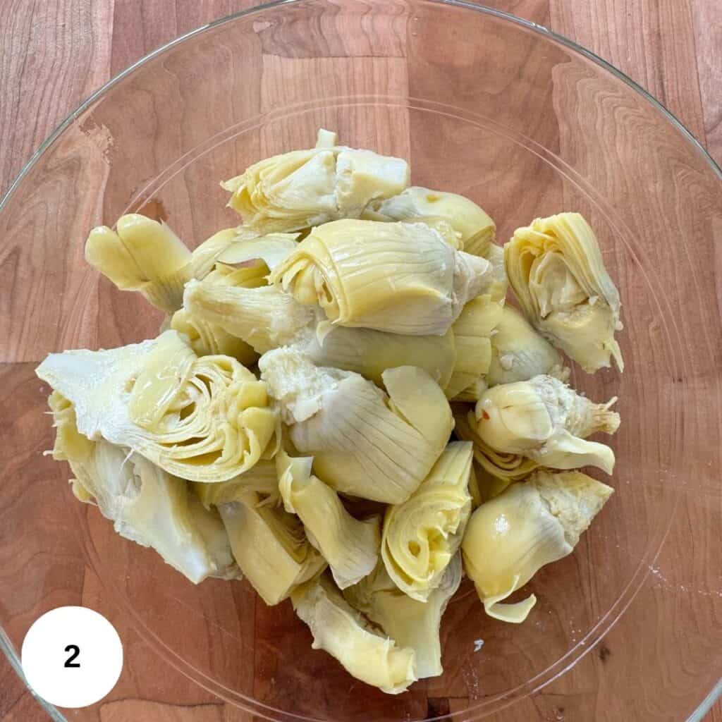 Drained artichoke hearts in a clear bowl.